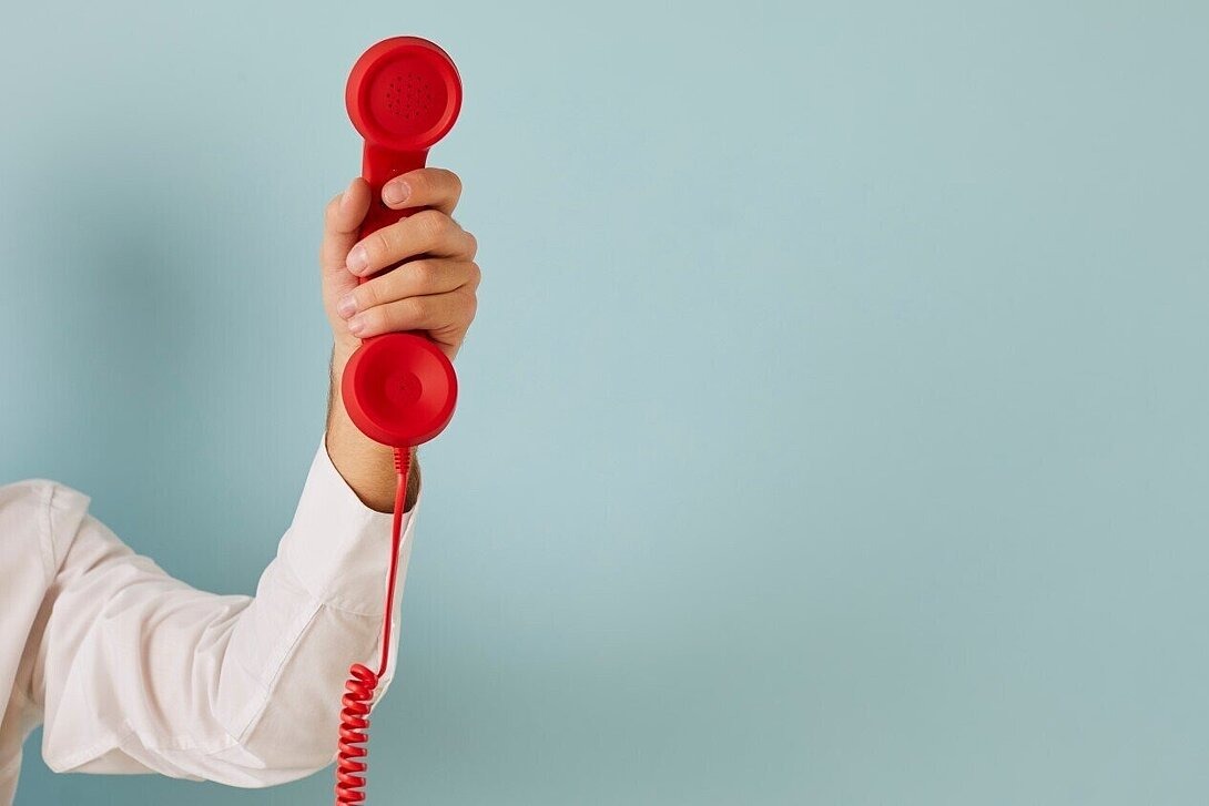 Person hält roten Hörer in der Hand als Beispielbild für eine Telefonberatung