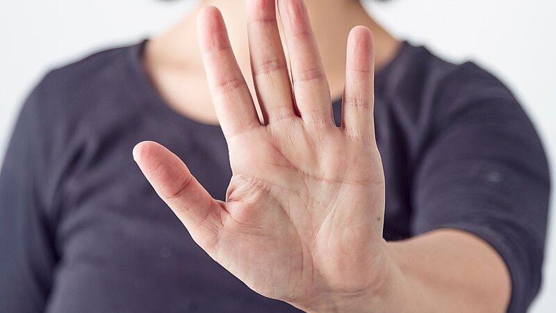 Eine Person hält die offene Hand mit der Handfläche nach vorne – als ruhige Stopp-Geste, die das Setzen klarer und fairer Grenzen symbolisiert., Bild: ondacaracola photography / gettyimages