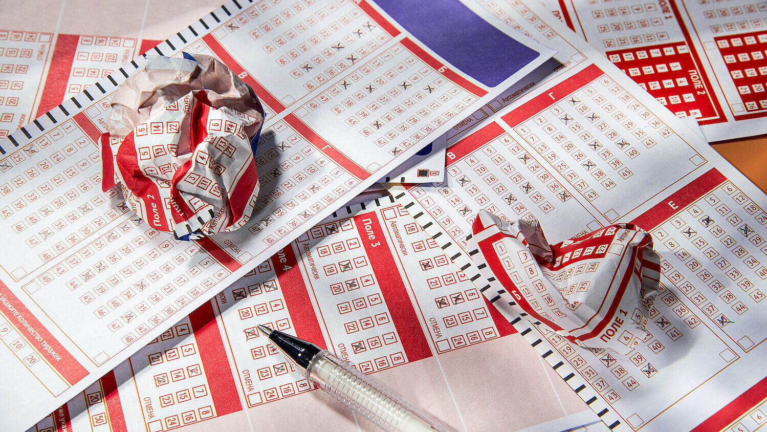 Zerknitterte Lottoscheine liegen auf ausgefüllten Lottoscheinen. 