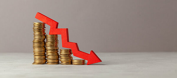 Gestapelte Münzen, die nach und nach kleiner werden, daneben ein roter Abwärtspfeil – Symbol für finanzielle Verluste durch Glücksspielsucht und das Risiko, in den Ruin zu geraten.