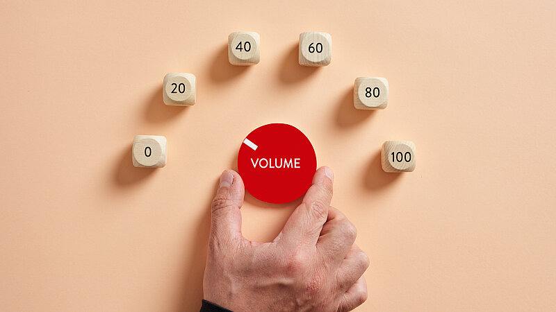 Ein Regler mit der Aufschrift "Volume" wird von einer Hand auf den zweitkleinsten Wert gedreht., Bild: Cagkan / adobe.stock.com