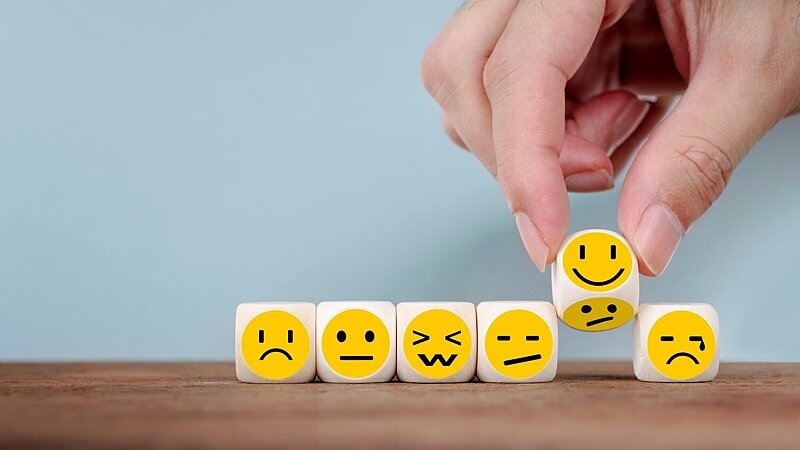 Mann dreht einen Emoticon-Wuerfel von einem traurigen zu einem gluecklichen Symbol, Bild: Mizkit / stock.adobe.com