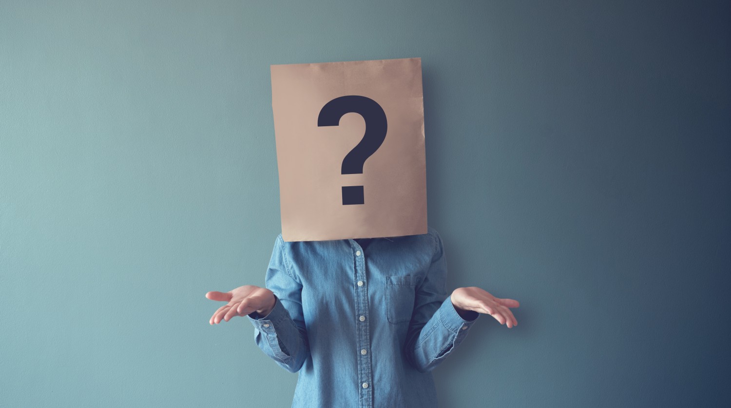 Eine Frau mit einer Papiertüte auf dem Kopf, auf der ein Fragezeichen abgebildet ist. Das Bild symbolisiert die Frage, was typische Persönlichkeitseigenschaften von Menschen mit problematischem Spielverhalten sind.